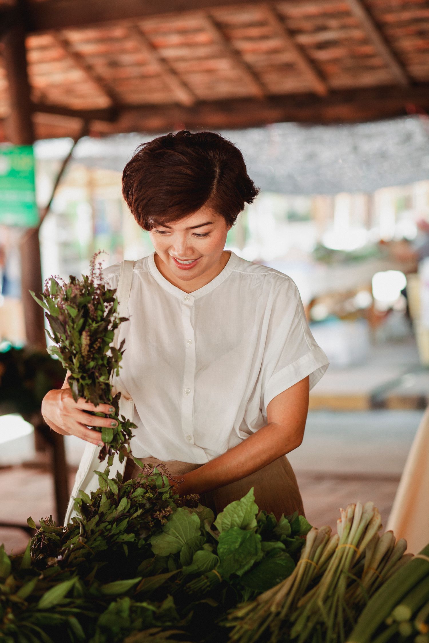 A shopper selecting fresh herbs at a local market